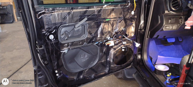 A car door panel interior showing the SoundSkins classic black installed with out speaker