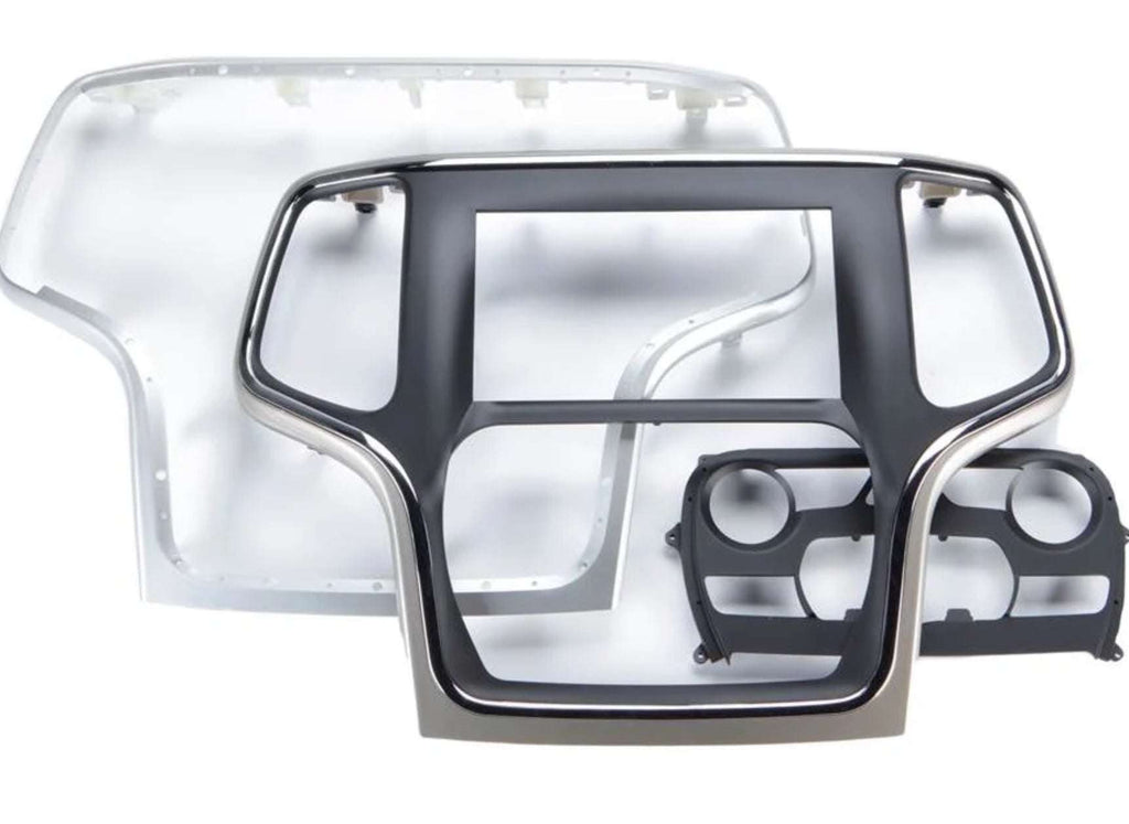 iDatalink KIT-JGC1 included dash components showing large silver and black Jeep Grand Cherokee radio surround bezel, inner chrome-trimmed head unit bezel, and black dual HVAC knob control module