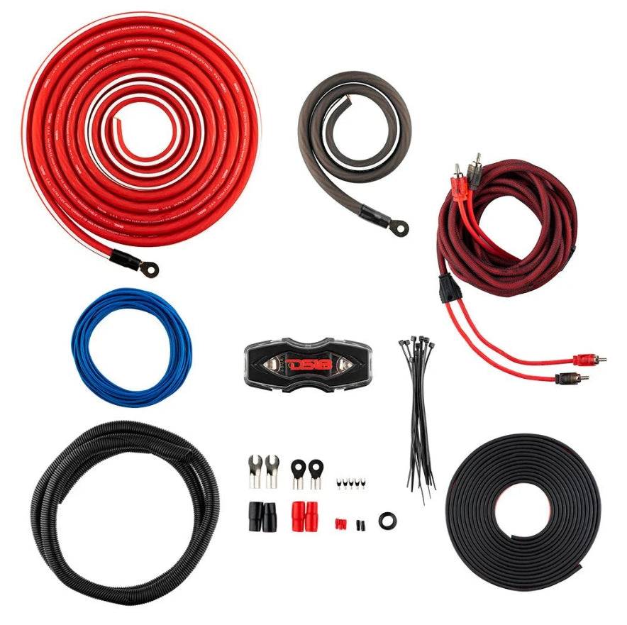 DS18 OFCKIT0 0-gauge OFC amplifier wiring kit components flat lay showing 17-ft red OFC power cable, 3-ft gray OFC ground cable, red, black twisted RCA cable, blue remote wire, ANL fuse holder, corrugated loom tube, split loom roll, fork and ring terminals, butt connectors, zip ties, and rubber grommet