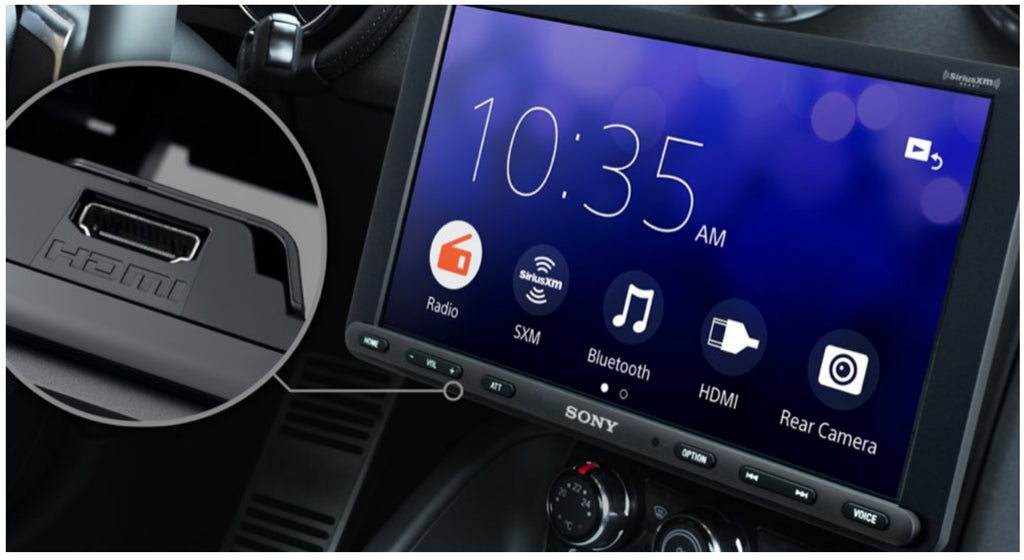 Sony XAV-AX8100 installed in vehicle dash showing home menu with 10:35 AM clock, Radio, SiriusXM, Bluetooth, HDMI, and Rear Camera icons with HDMI port location callout