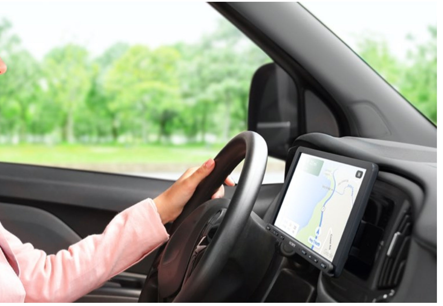 Sony XAV-AX8100 installed in vehicle showing navigation map on 8.95 inch touchscreen with driver's hand on steering wheel