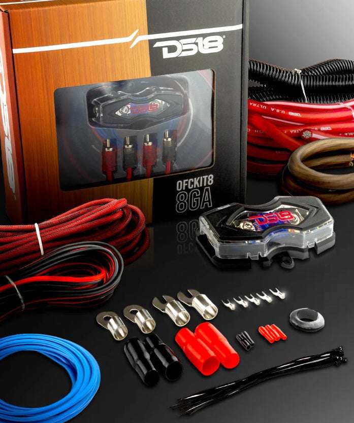 DS18 OFCKIT8 8-gauge OFC amplifier wiring kit lifestyle shot showing retail box, red OFC power cable, brown ground cable, red, black braided RCA cable, blue remote wire, DS18 ANL fuse holder, corrugated loom tube, ring terminals, fork terminals, butt connectors, zip ties, and rubber grommet