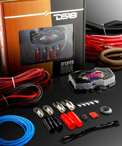 DS18 OFCKIT8 8-gauge OFC amplifier wiring kit lifestyle shot showing retail box, red OFC power cable, brown ground cable, red, black braided RCA cable, blue remote wire, DS18 ANL fuse holder, corrugated loom tube, ring terminals, fork terminals, butt connectors, zip ties, and rubber grommet